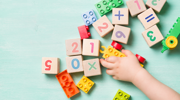 Stock image of child's hand playing with duplo and blocks.