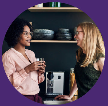 Stock image of two professional women talking by coffee machine.